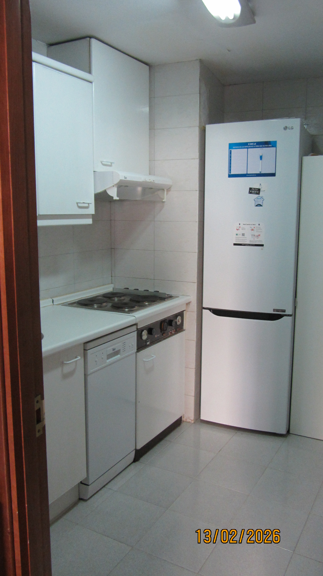 Cocina con mobiliario blanco, vitrocerámica, lavavajillas y frigorífico LG
