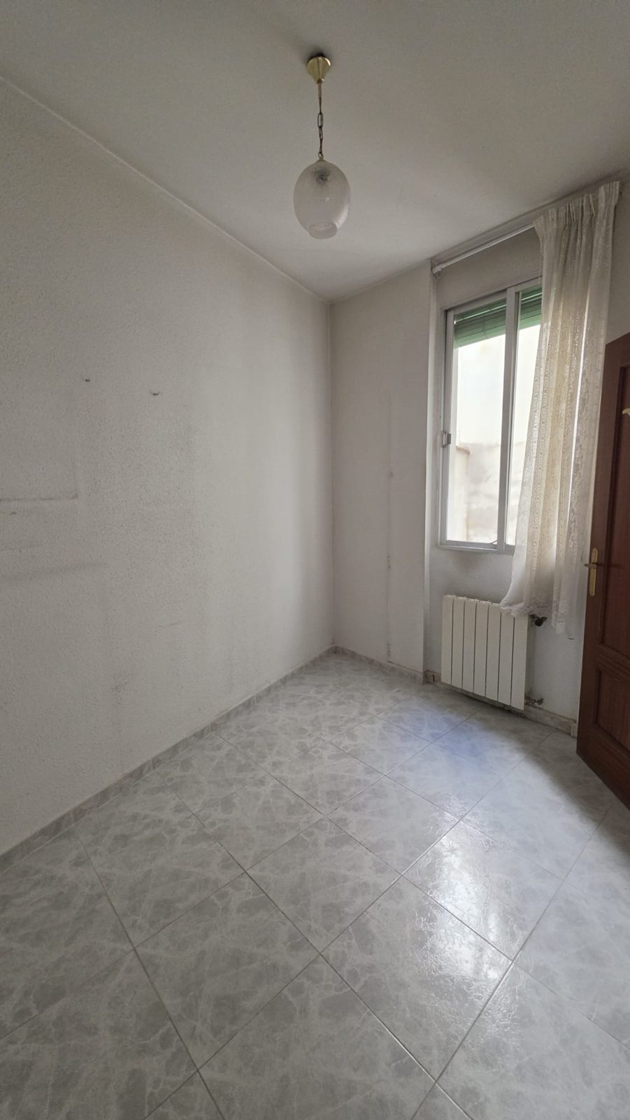 Habitación con ventana a patio, radiador y carpintería de madera