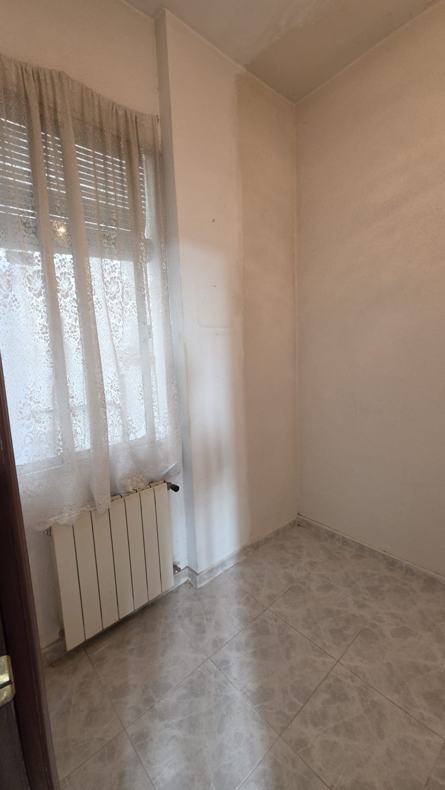 Vista de la segunda habitación desde la puerta, con ventana y radiador